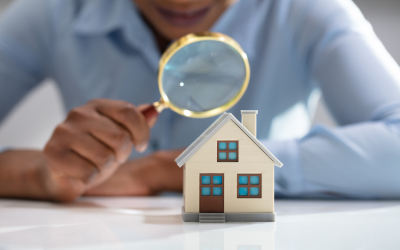 Home inspection concept with a model house and magnifying glass